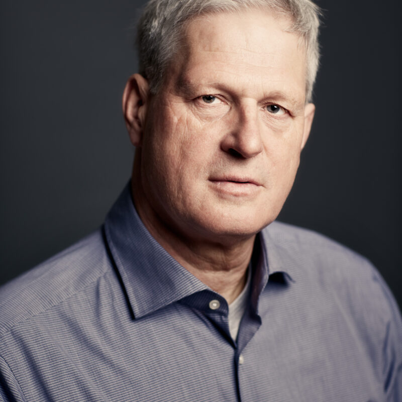 A head shot of a man wearing a grey shirt